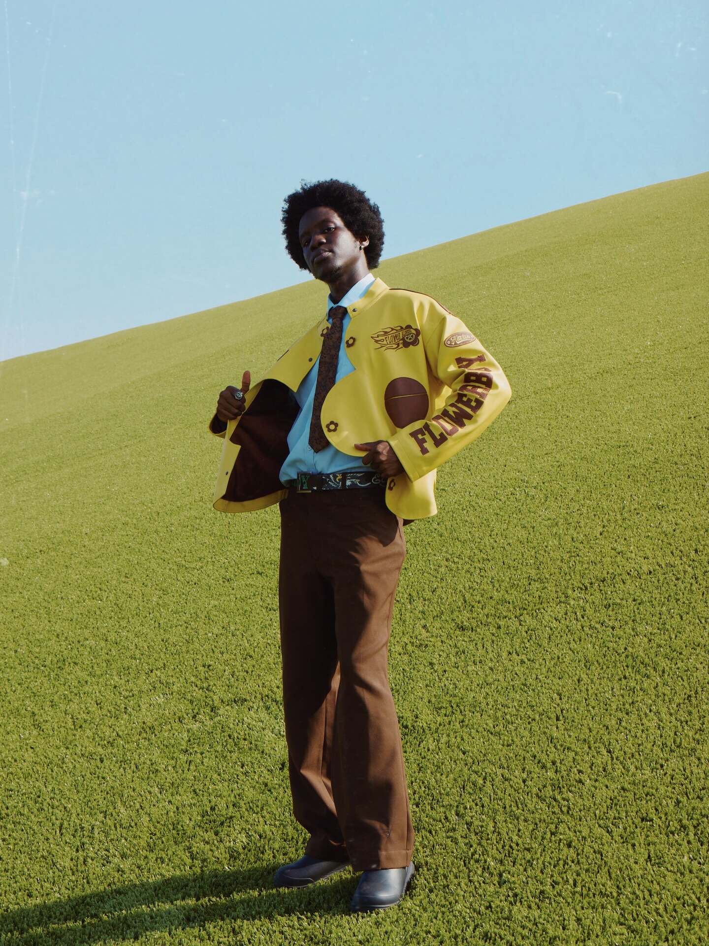 Hashim Samiru wearing the Flower Boy leather jacket on a grassy hillside